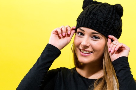 Girl wearing a cat knit hat on a yellow backgroundの写真素材