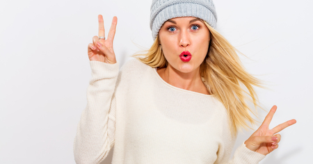 Young woman giving the peace sign on a white backgroundの写真素材