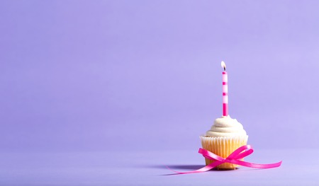 Cupcake with candle celebration theme on a purple backgroundの写真素材