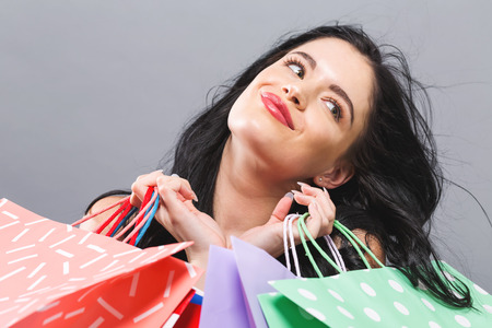 Happy young woman holding shopping bags on a gray background