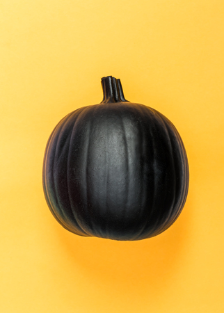 Halloweeen theme with a black pumpkin on a yellow backgroundの写真素材
