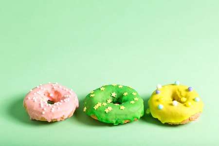 Colorful glazed donuts on a bright green backgroundの写真素材