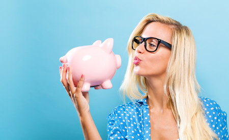 Young woman with a piggy bank on a blue backgroundの写真素材