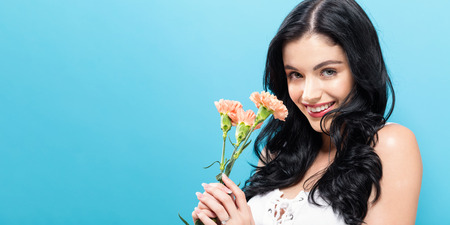 Young woman with carnaion on a blue backgroundの写真素材
