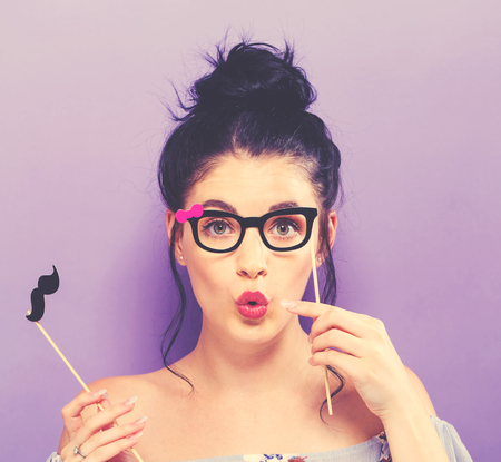 Young woman holding paper party sticks on a solid backgroundの写真素材