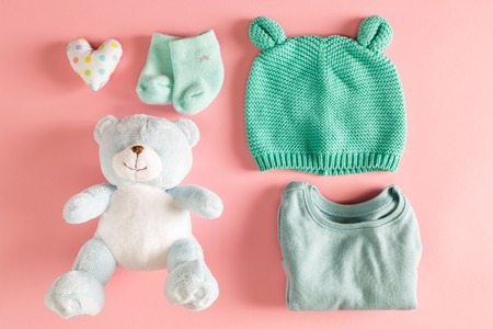 Baby clothes and teddy bear on a pink backgroundの写真素材