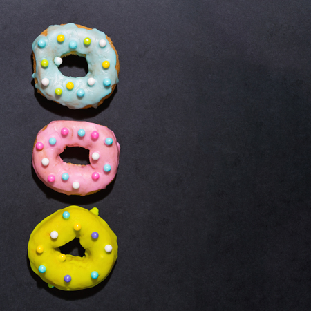 Colorful glazed donuts on a chalky black backgroundの写真素材