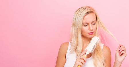 Beautiful woman holding a hairbrush on solid backgroundの写真素材
