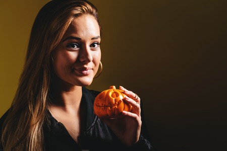 Young woman holding a pumpkin in halloween themeの写真素材