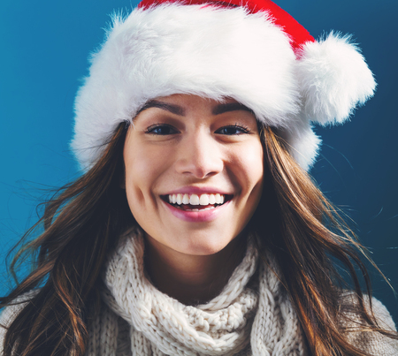 Happy young woman with Santa hat on a dark blue backgroundの写真素材