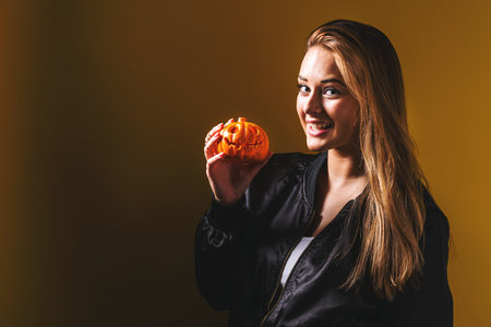 Young woman holding a pumpkin in halloween themeの写真素材