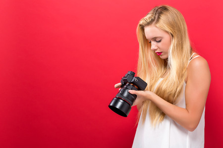 Young woman comparing professional camera on a solid backgroundの写真素材
