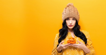Young woman holding a pumpkin in halloween theme