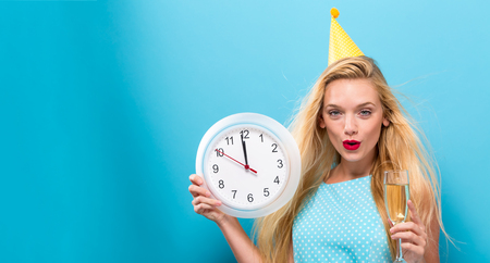 Young woman holding a clock showing nearly 12