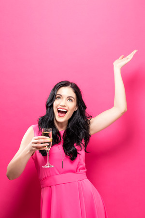 Young woman holding a champagne flute on a solid backgroundの写真素材