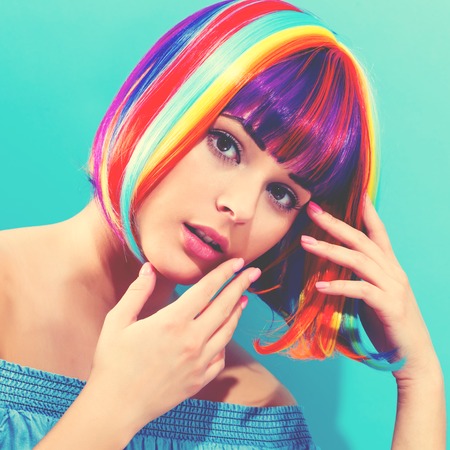 Beautiful woman in a colorful wig on a blue backgroundの写真素材