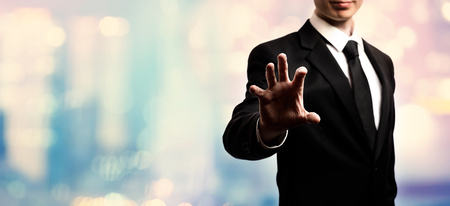 Businessman pointing his fingers on pink and blue abstract light backgroundの写真素材