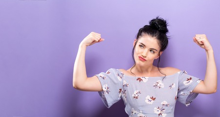 Powerful young woman in a success pose on a solid background