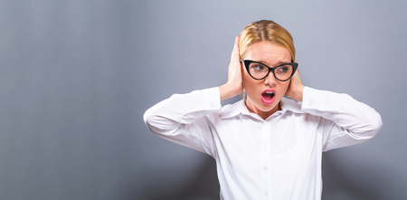 Young woman blocking her ears on a solid backgroundの写真素材