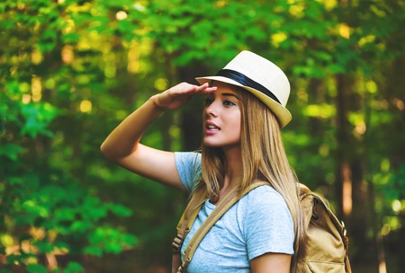 Young woman in the forest with a backpack and hatの写真素材