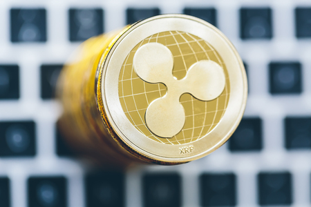 Stack of ripple coins with a laptop in the backgroundの写真素材