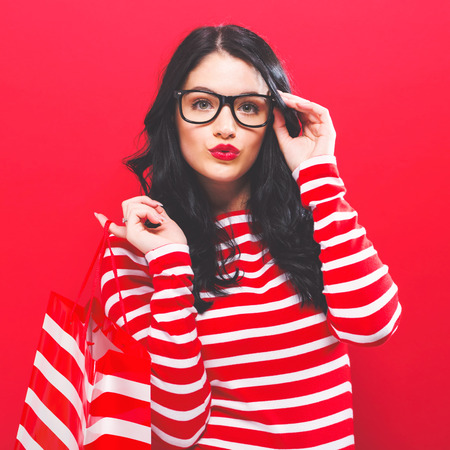 Young woman holding a shopping bag on a solid background