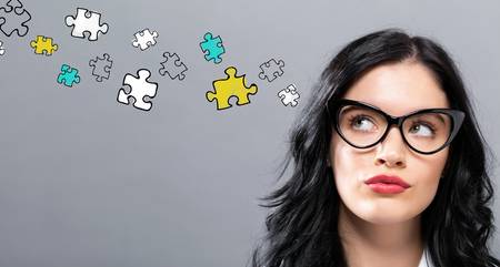 Puzzle Pieces with young businesswoman in a thoughtful face