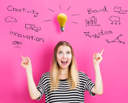 Young woman reaching and looking a yellow lightbulbの写真素材