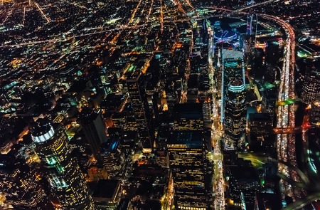 Aerial view of Downtown Los Angeles at night with young woman holding out a smartphone in her handの写真素材