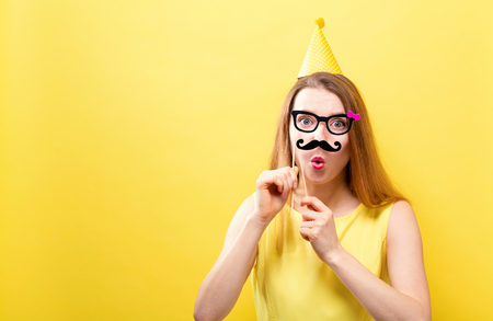 Young woman holding paper party sticks on a solid backgroundの写真素材