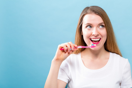 Young woman holding a toothbrush on a solid backgroundの写真素材
