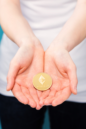 Woman holding a physical ethereum cryptocurrency coin in her hand