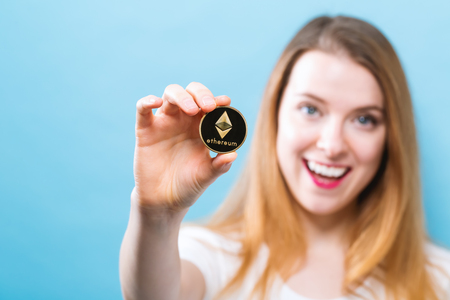 Woman holding a physical ethereum cryptocurrency coin in her hand