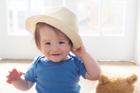 Happy toddler boy playing with a hatの写真素材