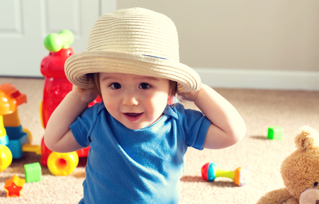 Happy toddler boy playing with a hatの写真素材