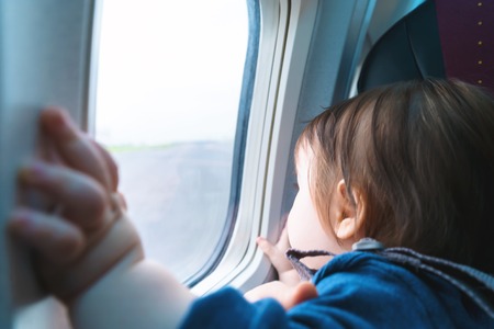 Little toddler boy looking out an airplane window while flying