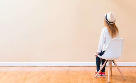 Young woman sitting in chair facing a big open wallの写真素材
