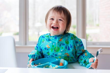Happy toddler boy with a big smile eating foodの写真素材