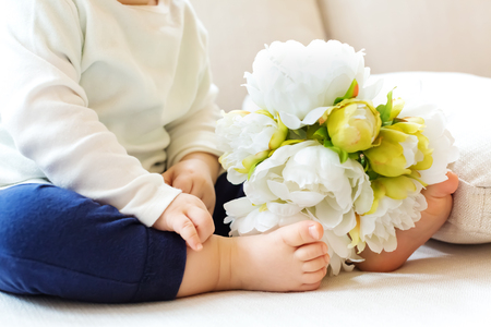 Toddler boy with spring flowers on a couchの写真素材