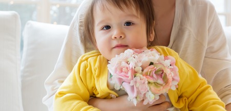 Happy toddler boy with his mother holding flowersの写真素材