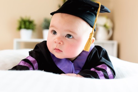 Little baby girl in graduation cap and gownの写真素材