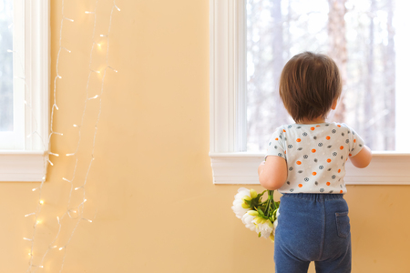 Toddler boy holding flowers in his houseの写真素材