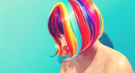 Beautiful woman in a colorful wig on a blue backgroundの写真素材