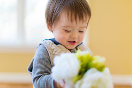 Toddler boy holding flowers in his houseの写真素材