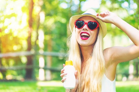 Young woman with sunscreen and sunglasses outside on a beautiful summer day