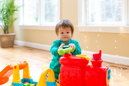 Happy toddler boy playing with toys in his house