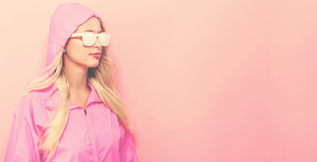 Fashionable woman in pink raincoat and sunglasses on a pink backgroundの写真素材