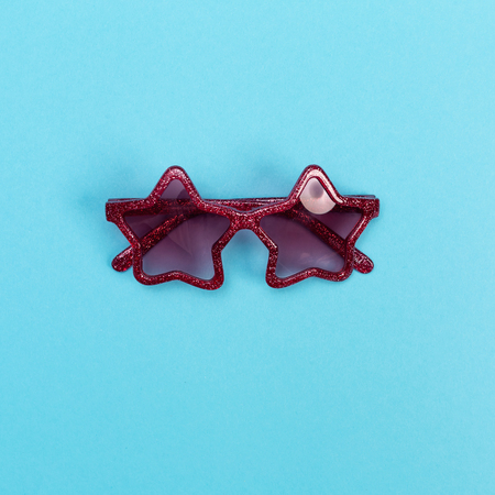 Cool sunglasses on a baby blue background, top view