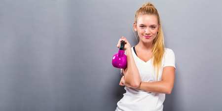 Happy young woman working out with a kettlebellの写真素材