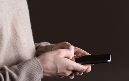 Mans hands using a smartphone on a black background